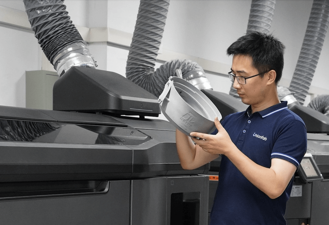 Unionfab CEO Allen Yang inspects a freshly printed part beside an HP Multi Jet Fusion (MJF) printer